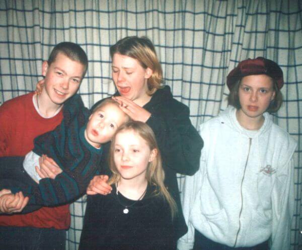 Conor with his siblings Sarah, Henry, Amelia and Nancy when they were children. Sarah, Henry and Amelia are teenagers, Nancy is around aged ten and Conor is about five. Henry is holding Conor horizontally while Sarah pats him on the head.