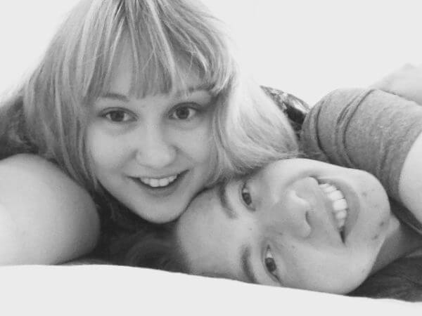 A black and white selfie of Conor and Laura lying down. Conor’s head is at an angle and Laura is resting her face on his.